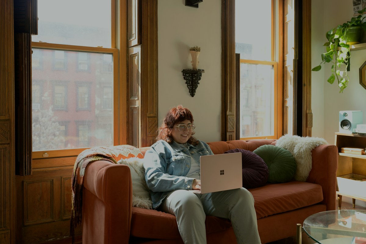 a woman sitting on a couch using a laptop computer